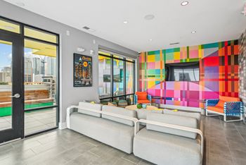 A living room with couches and a television and a colorful wall